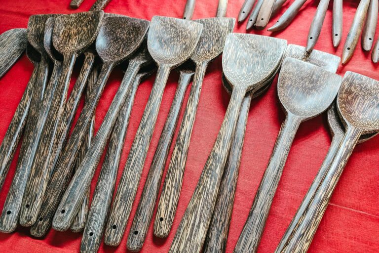 A collection of handcrafted wooden kitchen utensils displayed on a vibrant red background.