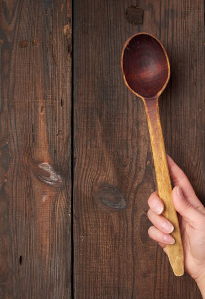 Hand holds an old brown wooden spoon, place for text