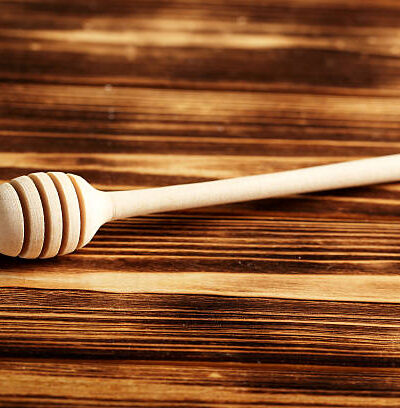 Wooden honey dipper on a brown wooden table
