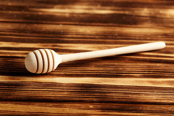 Wooden honey dipper on a brown wooden table