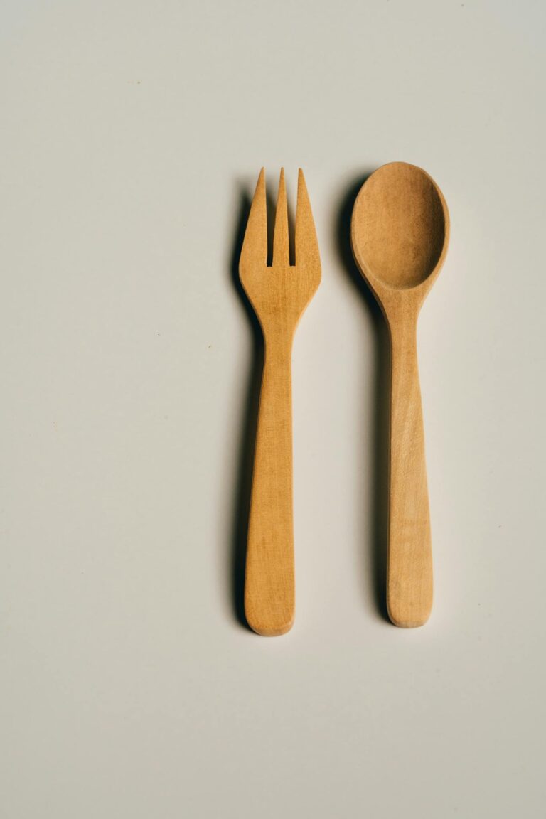 Vertical shot of a minimalist wooden fork and spoon on a neutral background.